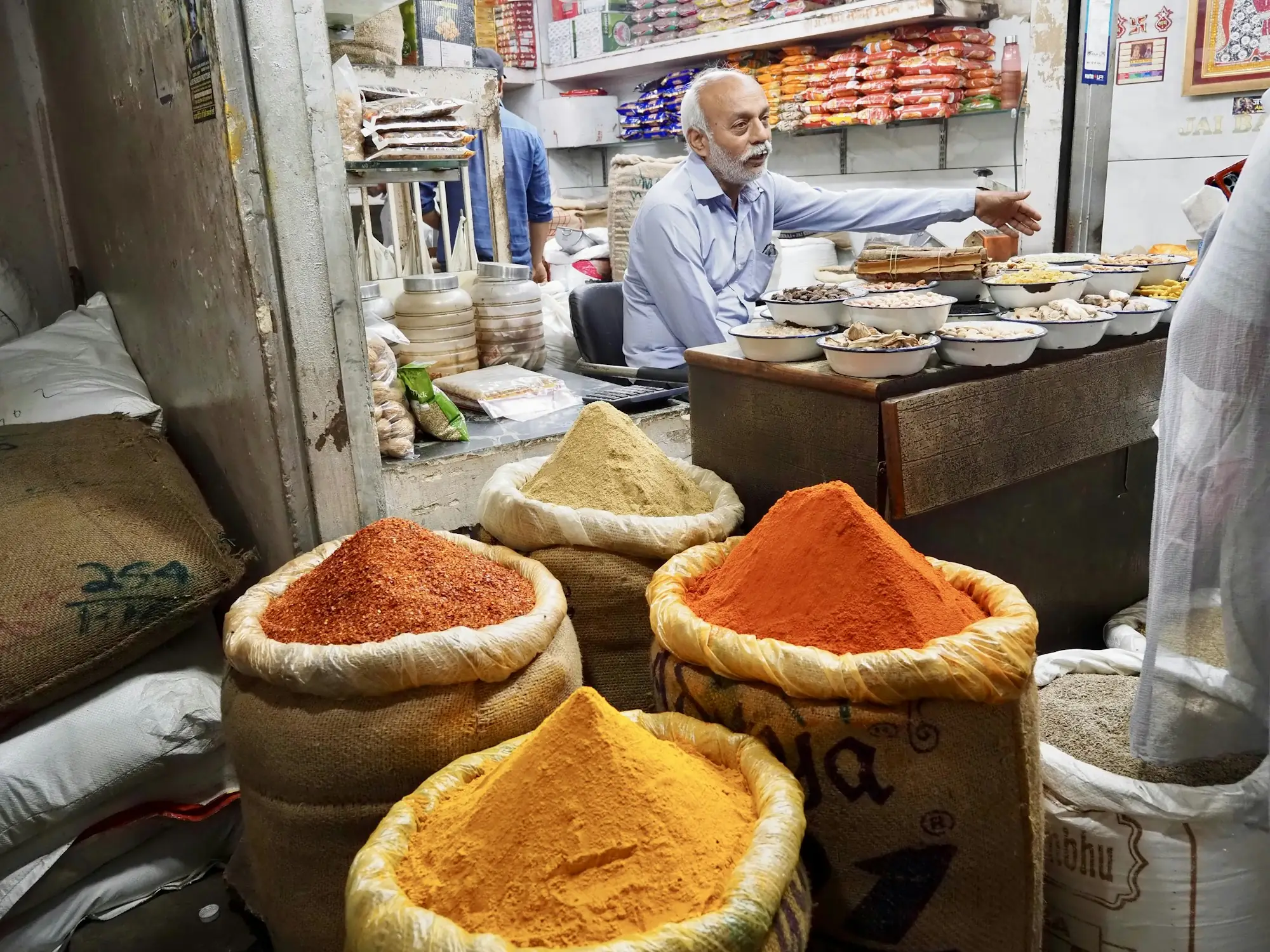 Spice trader with open sacks of turmeric and chilli powder at an Indian market